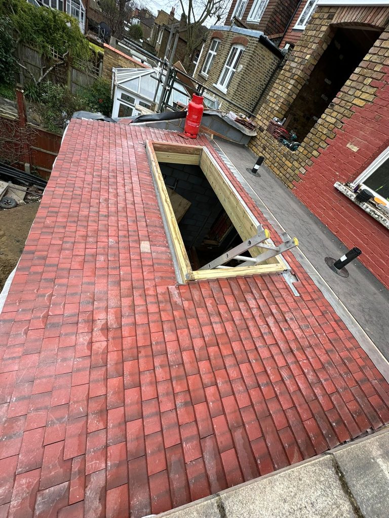 A newly tiled red roof with an opening for a skylight, part of a roofing project in Ealing by Glow Roofing